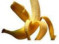 Iš dalies nuluptas geltonas bananas, kai kuriomis kalbomis vadinamas „bananų“, stovi baltame fone. Žievelė susisuka žemyn, atidengdama vaisius viduje, puikiai tinka bet kokiai dietai, ieškančiam natūralaus saldumo.