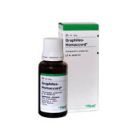 Graphites-Homaccord, homeopatinio vaisto, butelis grakščiai guli prieš baltą ir žalią pakuotę. Buteliukas turi traškų baltą dangtelį ir išsamią etiketę su lašų tekstu.