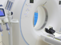 Artimas vaizdas šiuolaikinio kompiuterinės tomografijos aparato medicinos kabinete, kuriame matoma apvali anga, valdymo pultas, vaistų įvedimo sistema ir naudojimui paruoštas paciento stalas. Tiems, kurie procedūrų, pavyzdžiui, MRT tyrimo, metu gali patirti uždaros erdvės baimę, aplinkos supratimas gali padėti jaustis ramiau ir sužinoti, kaip išlaikyti ramybę per visą tyrimo laiką.